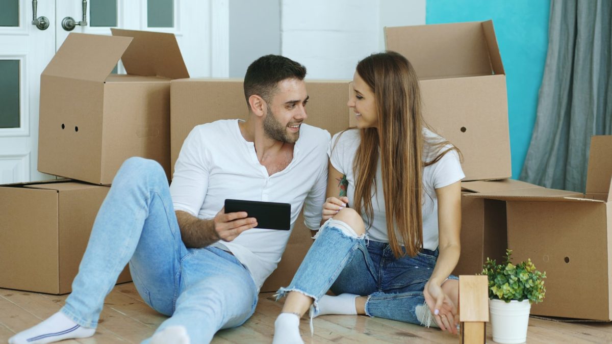 Couple portant des cartons de déménagement devant un immeuble