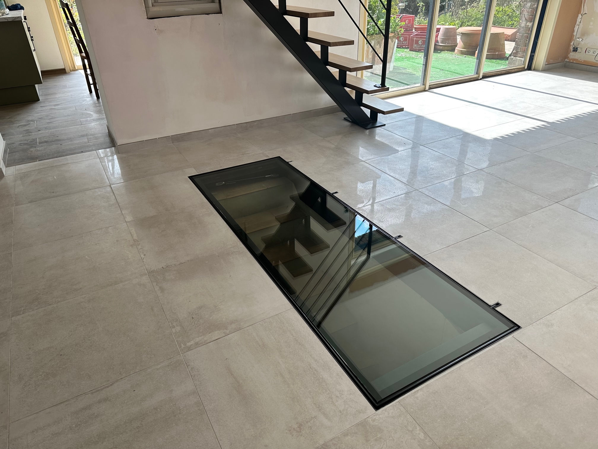 Trappe de cave vitrée encastrée dans un carrelage, escalier visible au travers du vitrage