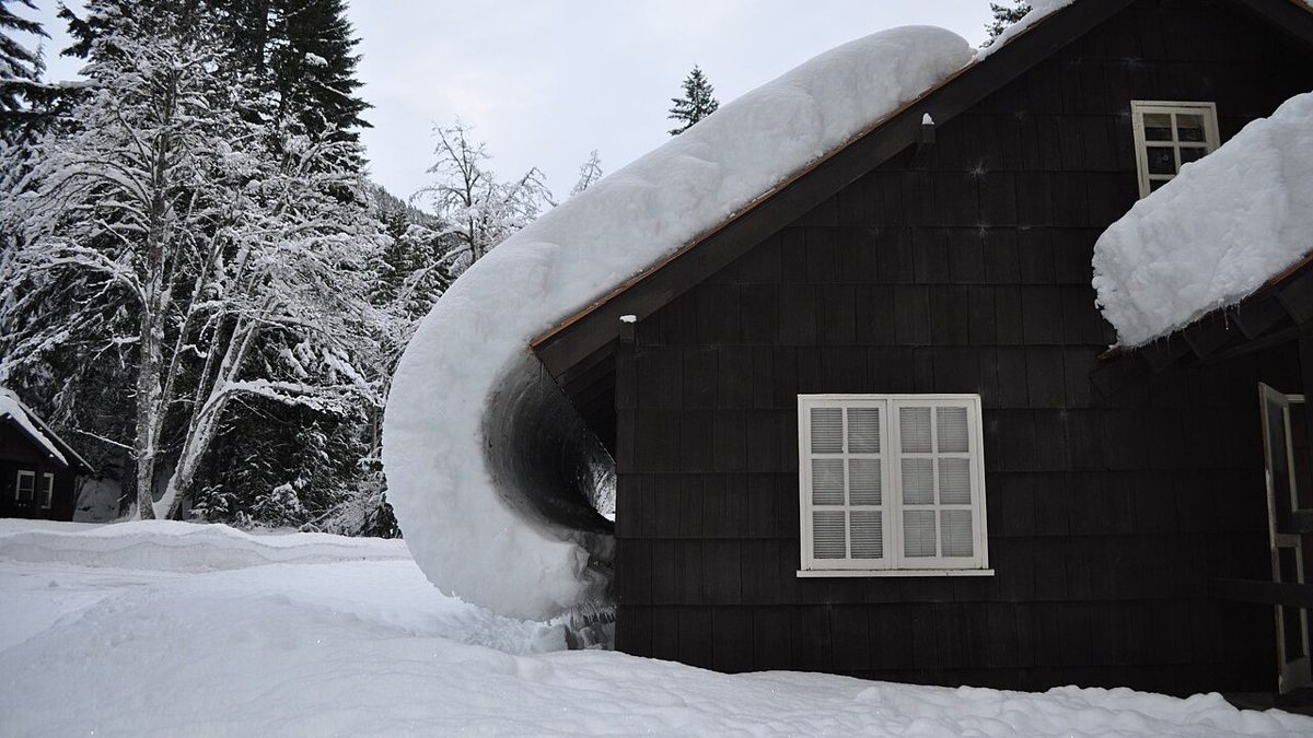Épaisse couche de neige qui glisse du toit d'un chalet en bois